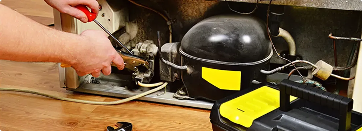 Refrigerator repair technician fixing the compressor and wiring in Dallas, TX